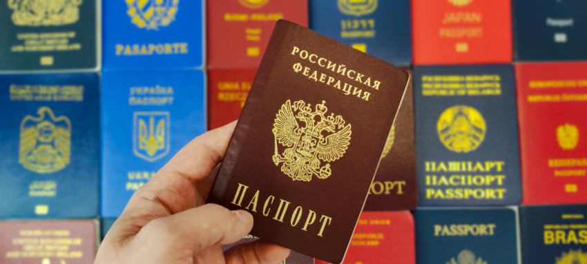 Человек держит паспорт Российской Федерации на фоне паспортов разных стран