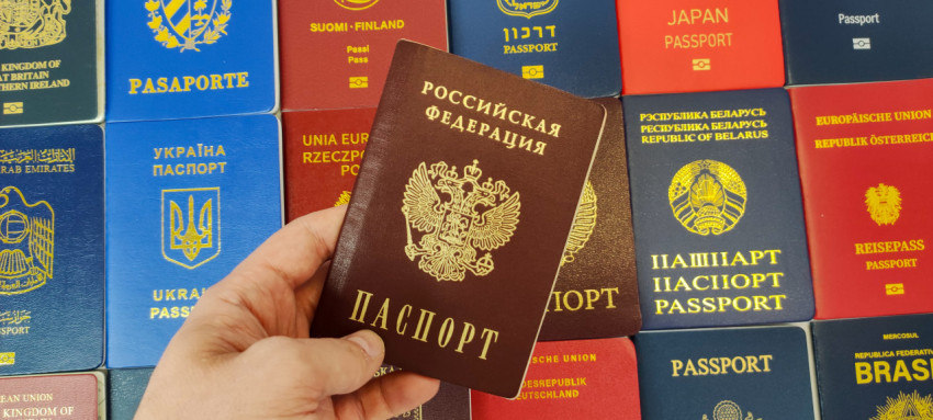 Рука держит российский паспорт на фоне международных паспортов