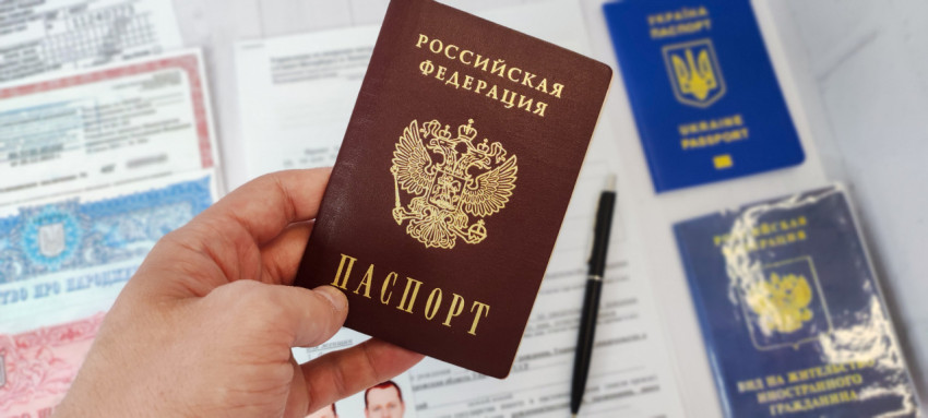 Паспорт гражданина РФ в руке на фоне миграционных документов
