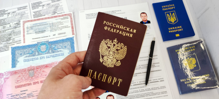 Рука с российским паспортом на фоне заявления и украинских документов