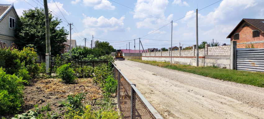 Щебёночная дорога в частном секторе с техникой для планировки покрытия