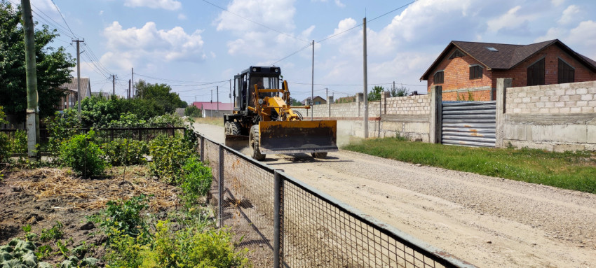 Автогрейдер на ремонте грунтовой улицы в частном секторе