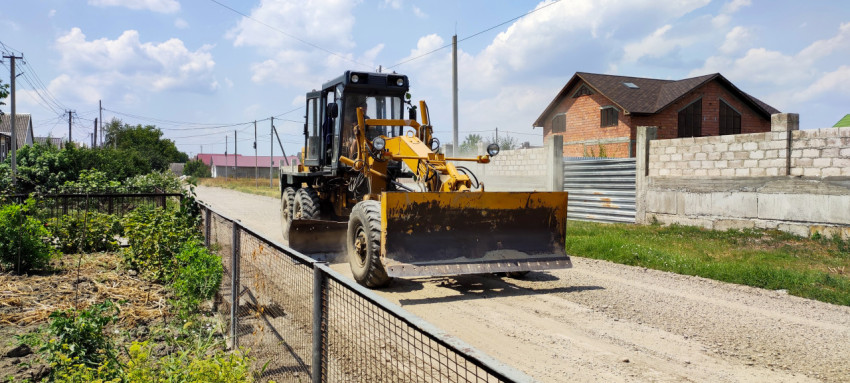 Автогрейдер на грунтовой дороге в частном секторе