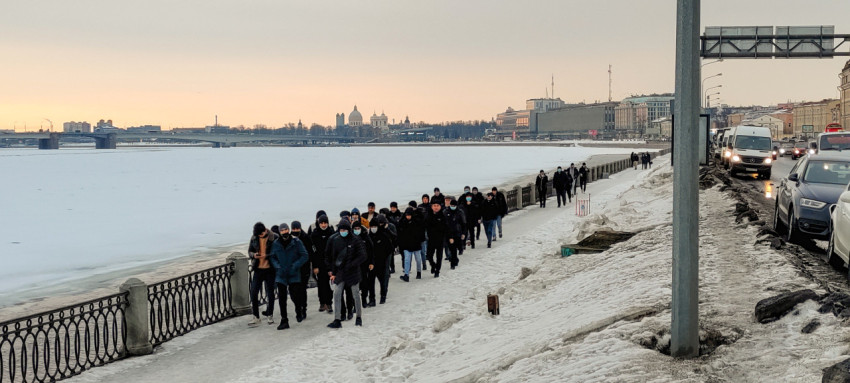 Толпа мигрантов проходит по набережной Невы в зимний день