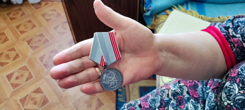 Медаль «Ветеран труда» в руке человека