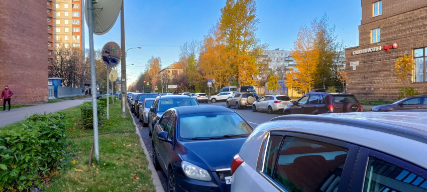 Осенняя улица с припаркованными автомобилями и городскими пейзажами