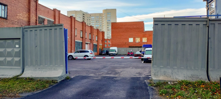 Парковка возле промышленного здания с шлагбаумом