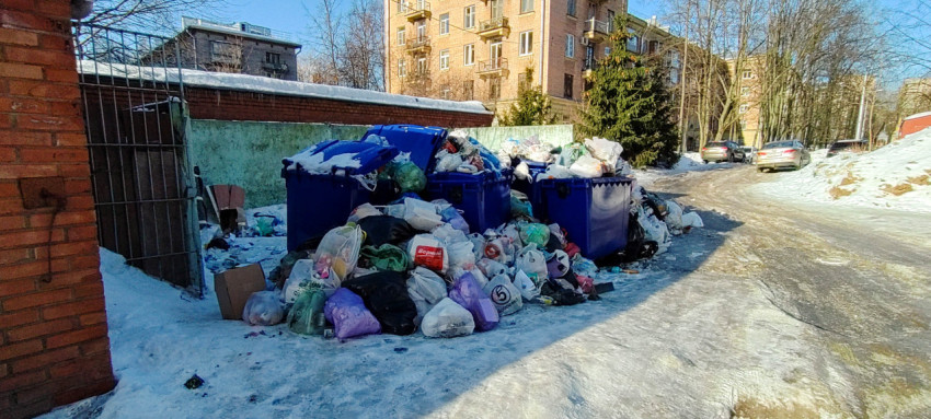 Переполненные мусорные контейнеры во дворе многоэтажного дома