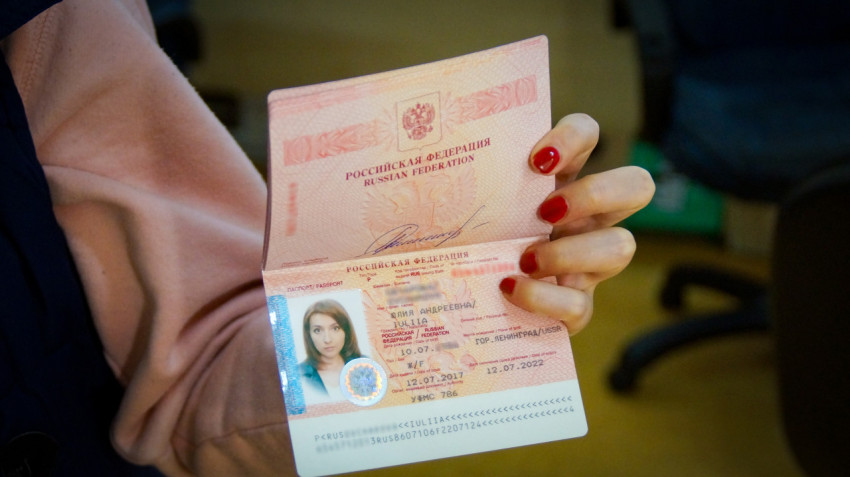 Девушка держит открытый загранпаспорт в руке