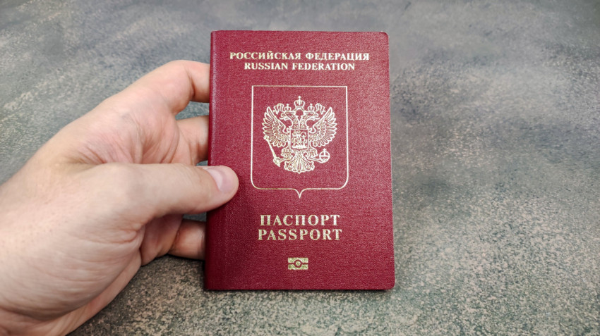 Биометрический загранпаспорт РФ в руке на фоне серой поверхности