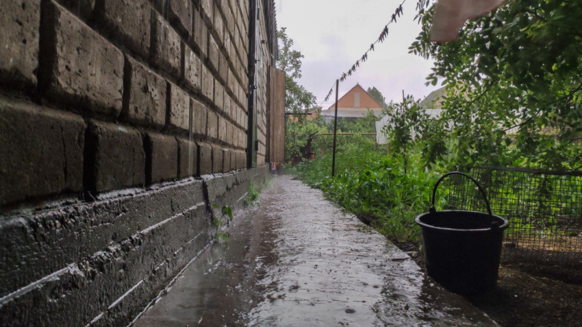 Дождевая вода на дорожке у кирпичного дома в саду