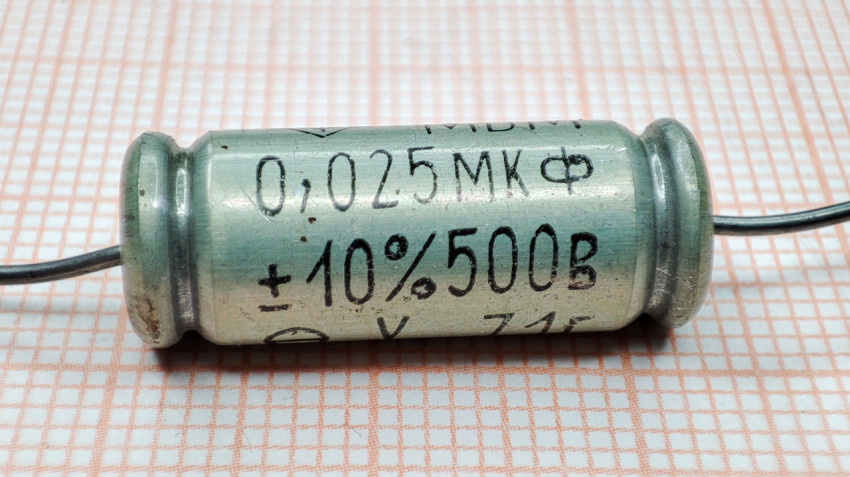 Крупный план металлобумажного конденсатора МБМ на бумаге в клетку
