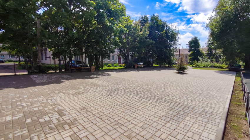 Площадка с тротуарной плиткой и скамейками во дворе
