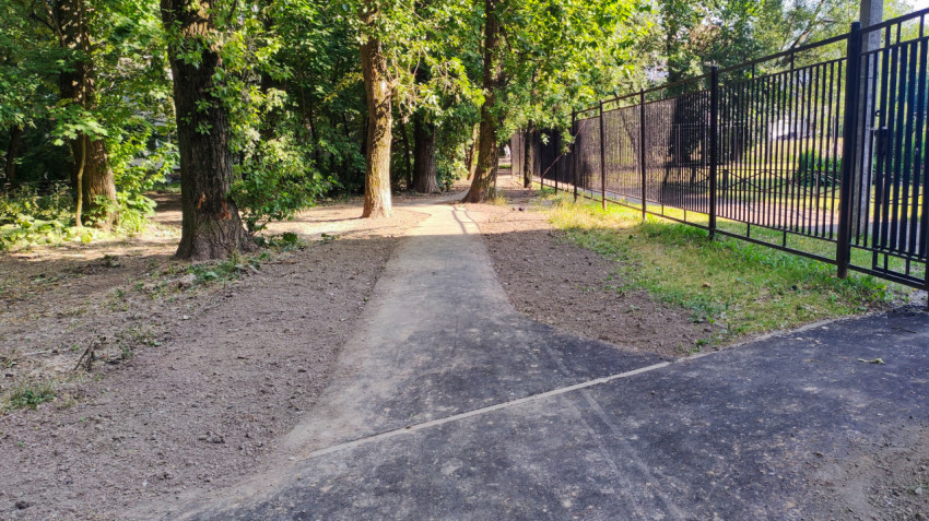 Асфальтированная дорожка вдоль ограждения в парковой зоне