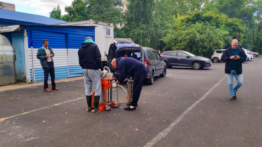 Рабочие готовят бурильное оборудование для проверки асфальта