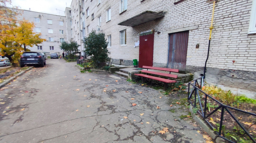 Подъезд жилого дома с лавочкой и клумбой во дворе