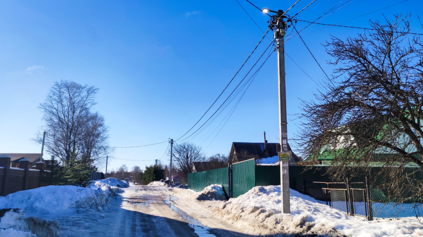 Загородная улица с линией электропередачи и сугробами