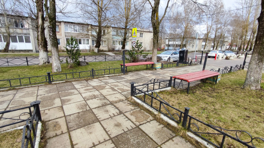 Мемориальная зона с лавочками и ограждениями рядом с городской улицей