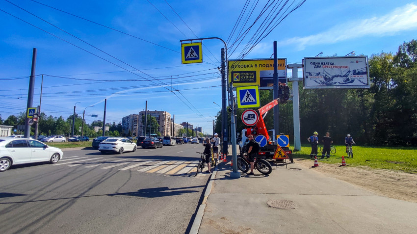 Спецтехника и рабочие у рекламных конструкций на перекрестке