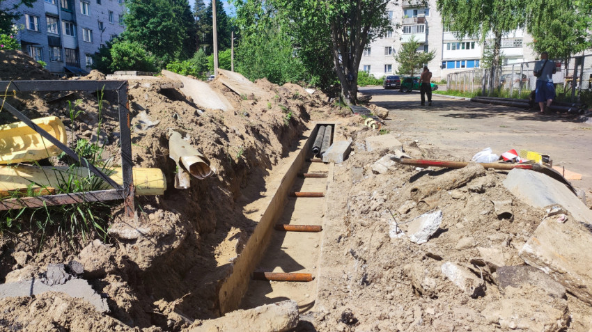 Длинная траншея и строительные материалы при ремонте коммуникаций во дворе