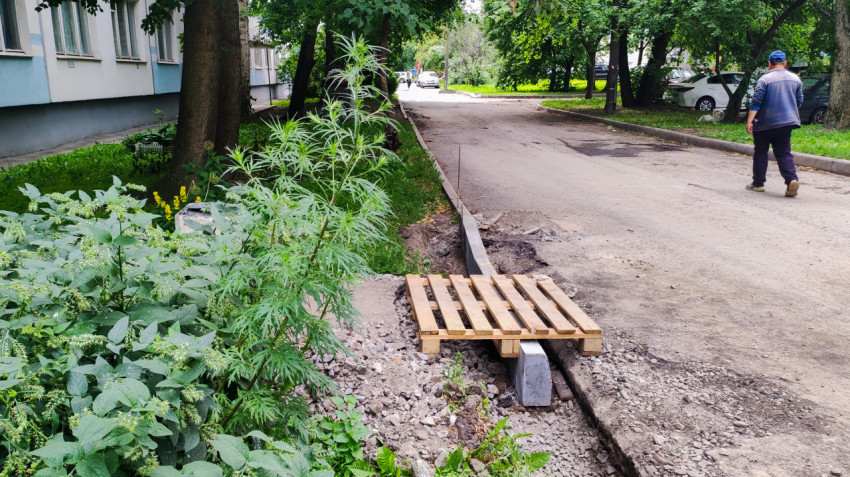Временный мостик из деревянного поддона через раскопку у бордюра во дворе жилого дома