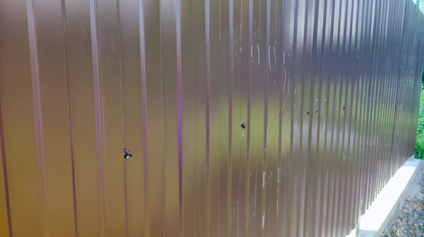 Коричневый металлический забор из профнастила на бетонном основании