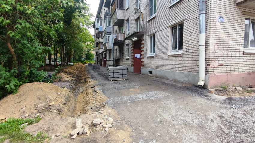 Ремонт дворовой территории у кирпичного дома с траншеей и складированными плитами