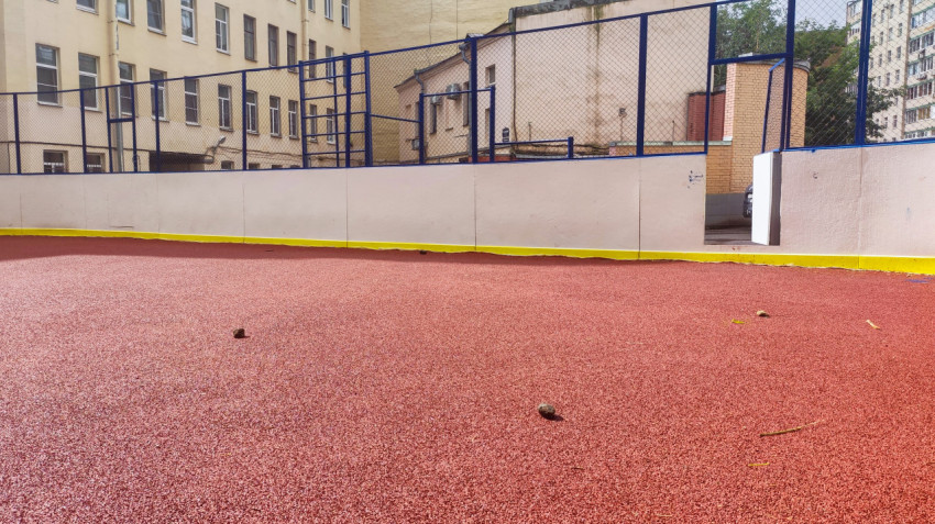 Фактура красного резинового покрытия на дворовой спортивной площадке