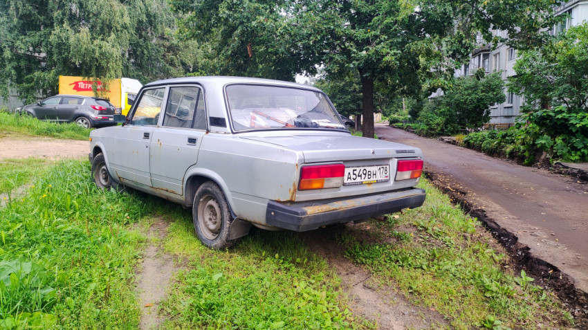 Старый седан Lada припаркован на газоне рядом с разрытым дворовым проездом