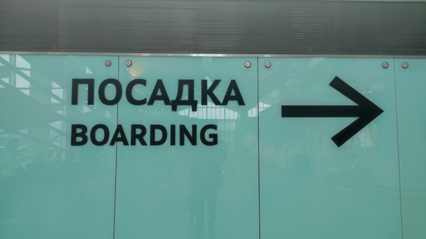 Указатель «Посадка / Boarding» на стекле, стрелка показывает проход