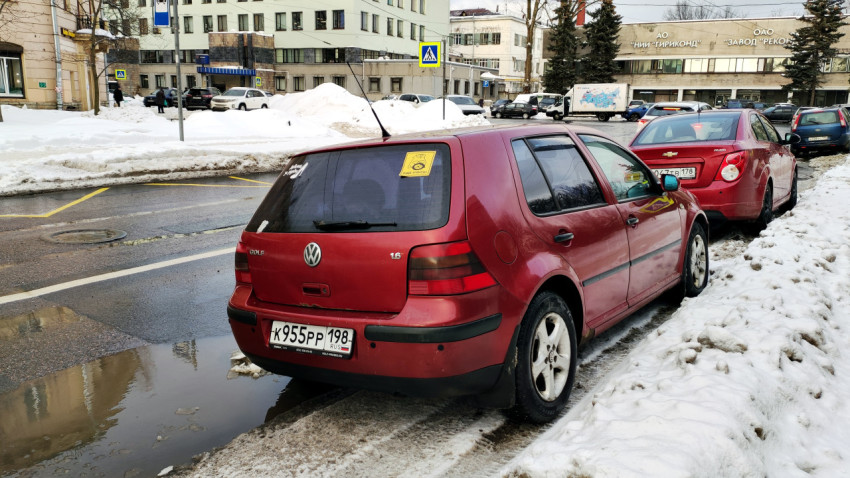 Красный автомобиль припаркован на обочине заснеженной дороги