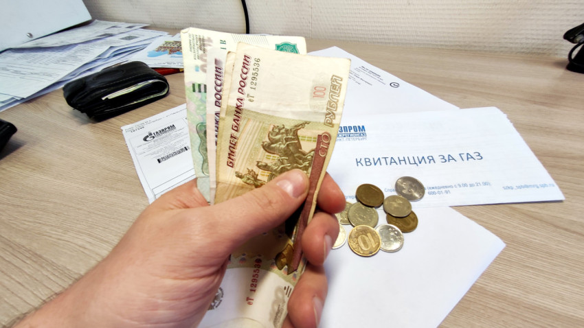 Деньги в руке на фоне квитанций за коммунальные услуги
