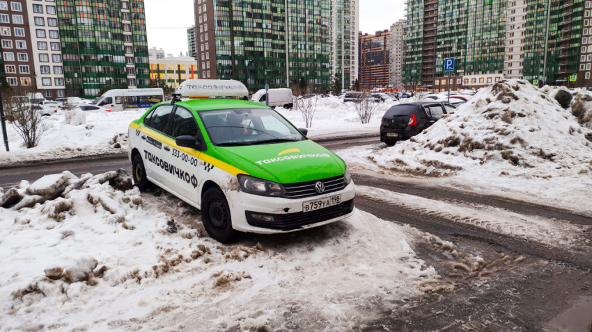 Такси с яркой расцветкой стоит на снегу в зимнем городе