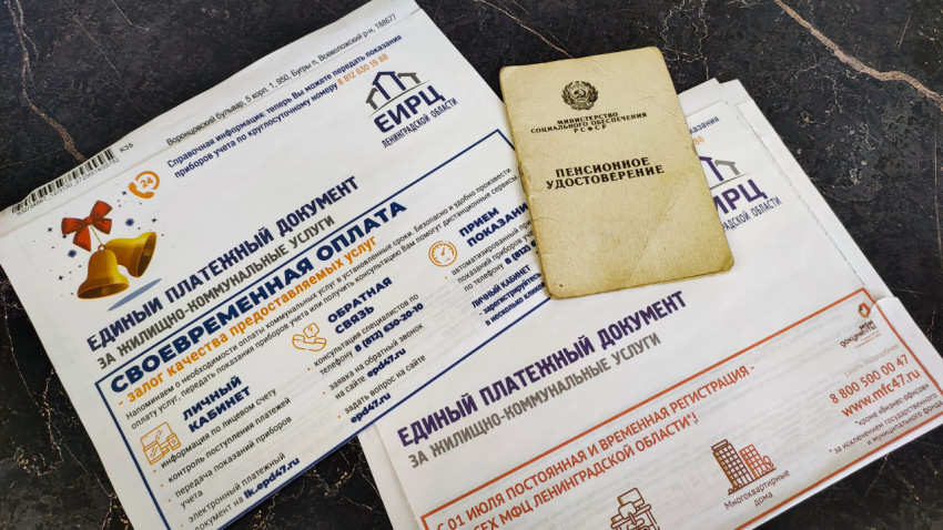 Старое пенсионное удостоверение и квитанции за коммунальные услуги на столе