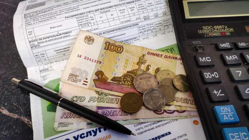 Деньги, калькулятор, ручка и квитанция на уплату взноса на капитальный ремонт дома