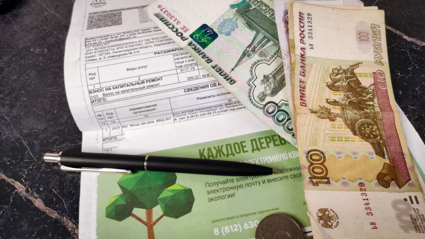 Деньги, ручка и квитанция об оплате взноса на капитальный ремонт дома