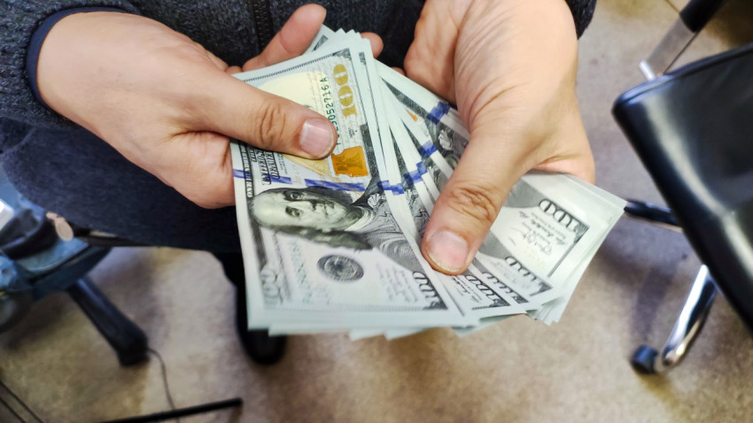 Человек держит кучу долларов США в руках