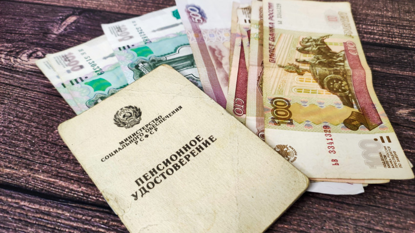 Пенсионное удостоверение и российские рубли на деревянном столе