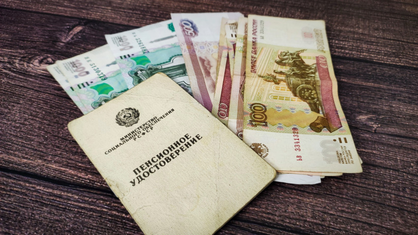 Пенсионное удостоверение и денежные купюры на деревянном столе
