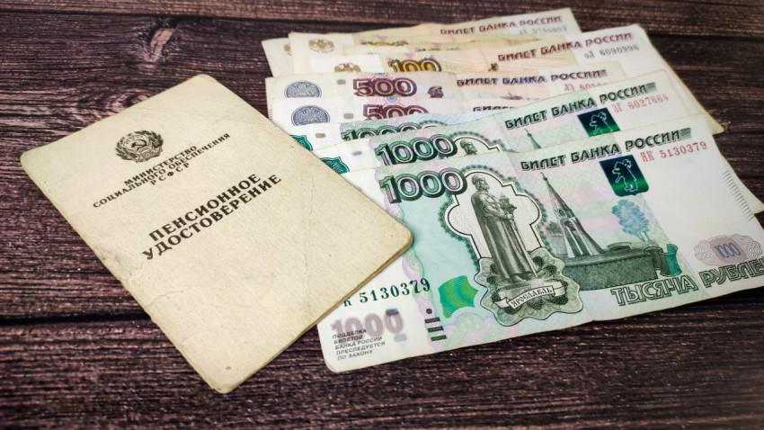 Пенсионное удостоверение и деньги в русских рублях на деревянном столе