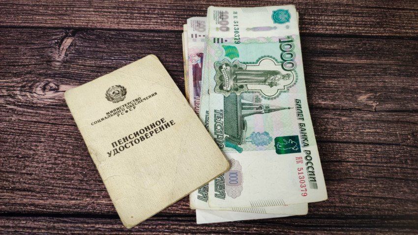 Пенсионное удостоверение и рубли на деревянном столе