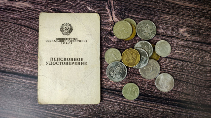 Пенсионное удостоверение и монеты на деревянном столе