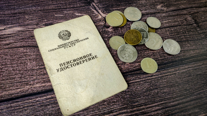 Пенсионное удостоверение и мелочь на деревянной поверхности