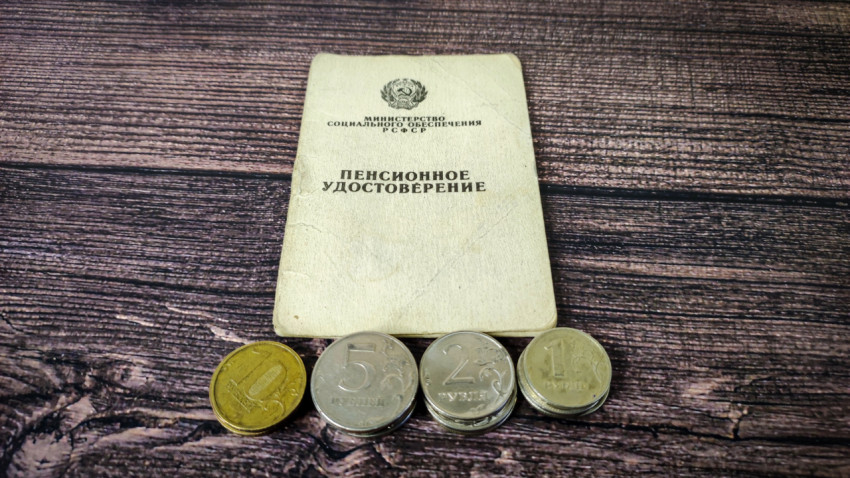 Монеты и пенсионное удостоверение на деревянном столе