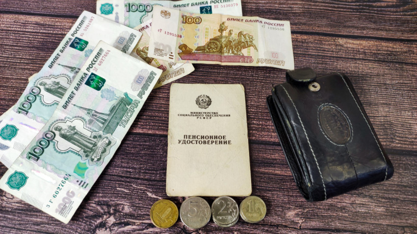 Пенсионное удостоверение на фоне денег, монет и кошелька