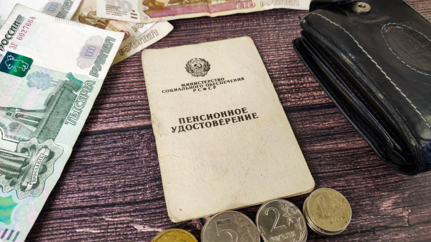 Пенсионное удостоверение, деньги, монеты и кошелек на столе