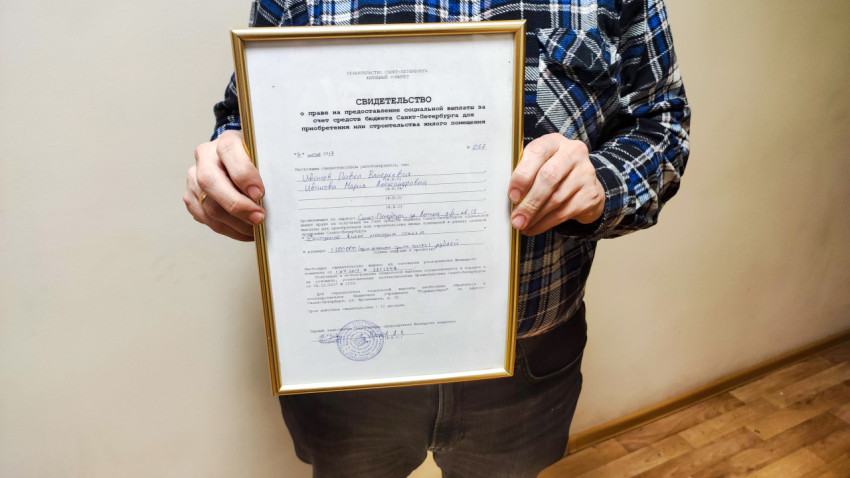 Мужчина держит сертификат на покупку квартиры от государства