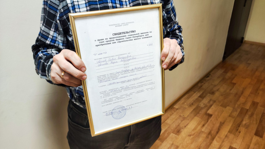 Человек держит сертификат на покупку квартиры от государства