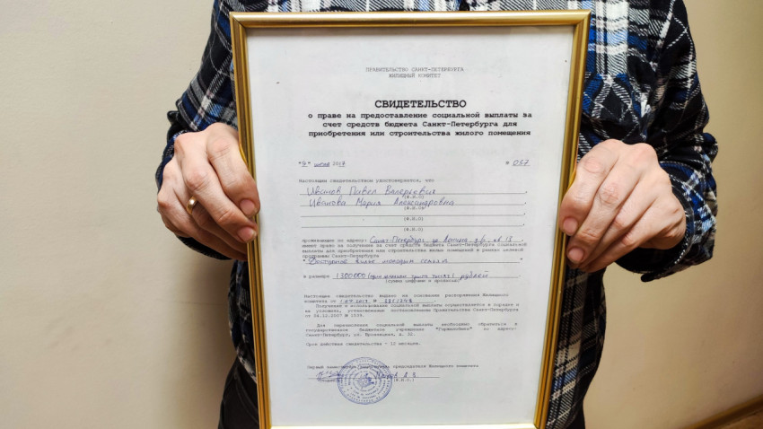 Мужчина держит сертификат на покупку квартиры