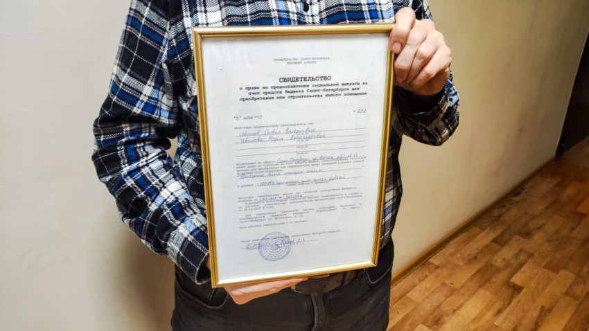 Мужчина держит свидетельство на покупку квартиры от государства